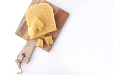 Parmesan cheese, on a wooden board and on a white background. Traditional food. Free space for text. Top view