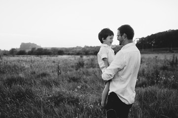 Handsome dad with his little cute son are having fun and playing on green grassy lawn. Happy family concept. Beauty nature scene with family outdoor lifestyle. family resting together. Fathers day