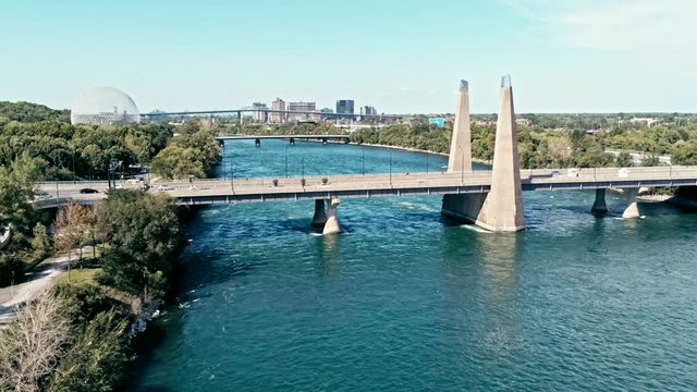 aerial drone footage of montreal with bridges and a park area plus ile sainte helene island with the biosphere dome in the background
