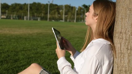 A tablet and a beautiful young woman in a park.