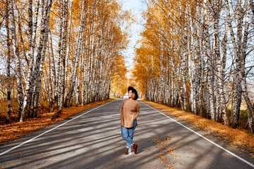 Portrait of an autumn woman over golden leaves. Woman walking in park at autumn season