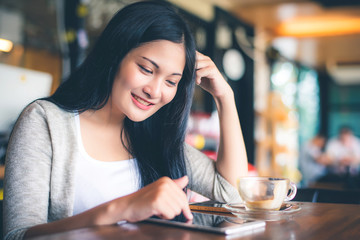 Beautiful attractive young Asian woman using smart phone or cellphone at cafe or coffe shop in the morning 