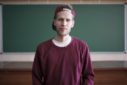 cool young hipster student in snapback cap and casual in university with blackboard on background