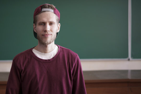 cool young hipster student in snapback cap and casual in university with blackboard on background