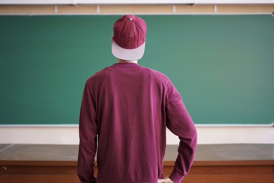cool young hipster student in snapback cap and casual in university with blackboard on background
