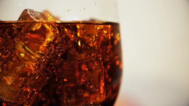 Cola in the glass with Ice cubes and bubbles rotating. Food background. Soda Close-up.