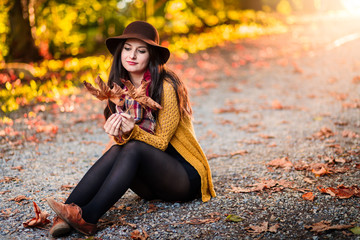 Girl in a park with autumn leaves around her.