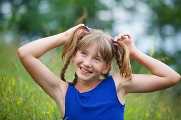Obraz premium School-age girl in a blue dress with two long braids.
