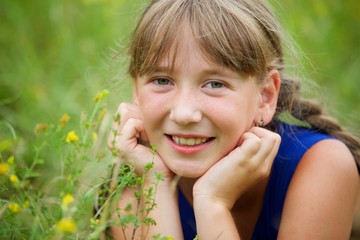 Fototapeta premium School-age girl in a blue dress with two long braids.