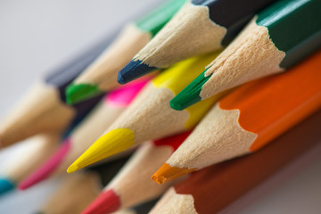 Pile of sharp coloured drawing pencils on table. Rainbow colors  red, yellow, blue, green, purple. Concept of art, crafts and kids having fun