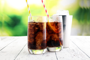 Softdrink with ice cubes, lemon and straw in glass