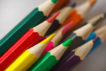 Fototapeta premium Pile of sharp coloured drawing pencils on table. Rainbow colors red, yellow, blue, green, purple. Concept of art, crafts and kids having fun