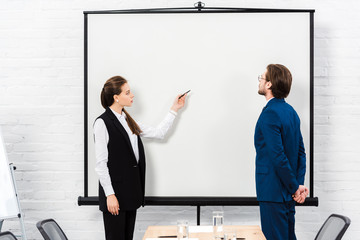 businesswoman making presentation and pointing at blank whiteboard at modern office