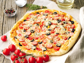 Homemade big pizza with parmesan, oregano, olives and mozzarella, sausage and tomato sauce, side view