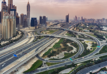 Aerial view on Dubai Marina, UAE, with big highway intersection and skyscrapers in the distance. Scenic travel background.