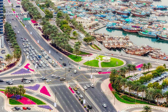 Road intersection and port in Deira city center in Dubai, UAE. Aerial view on crossroads with city traffic and boats.