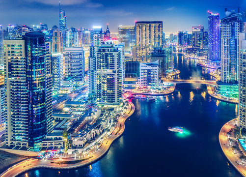 Scenic nighttime skyline of big modern city with illuminated skyscrapers. Aerial view of Dubai Marinai, UAE. Multicolored travel background.
