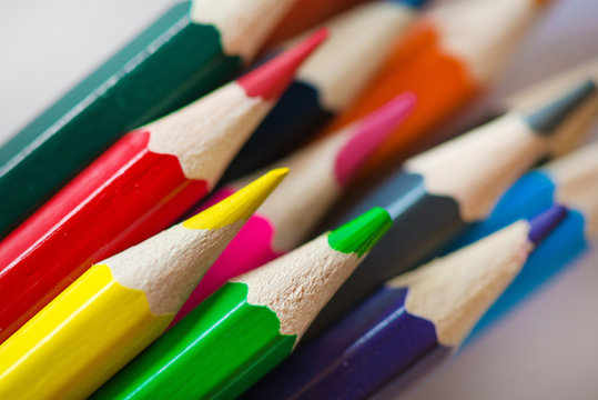 Pile of sharp coloured drawing pencils on table. Rainbow colors  red, yellow, blue, green, purple. Concept of art, crafts and kids having fun