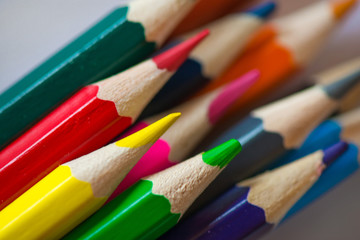 Pile of sharp coloured drawing pencils on table. Rainbow colors  red, yellow, blue, green, purple. Concept of art, crafts and kids having fun