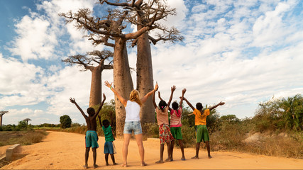 woman exult with black children and greating a baobab tree, concept of african united