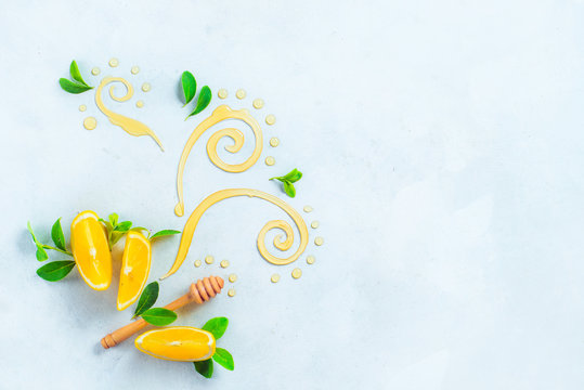 Honey dipper with decorative honey swirls and lemon slices on a white wooden background with copy space. Creative food photography from above. Painting with food concept