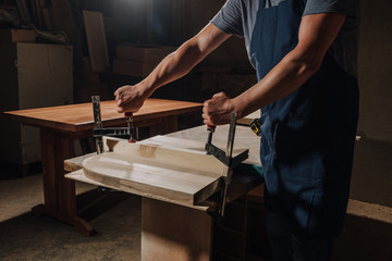 cropped shot of carpenter in apron working on wood at workshop