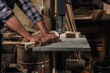 partial view of woodworker using electric drill on wood at workshop