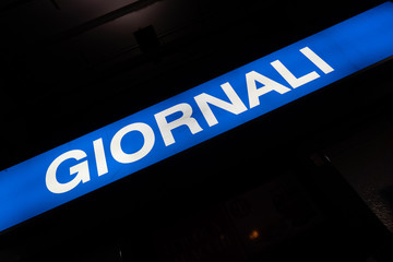 Blue signage of Giornali, Italian for Newspapers, on a black background