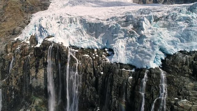 Front of glacier, big crevasses and waterfall. Aerial view from a drone.