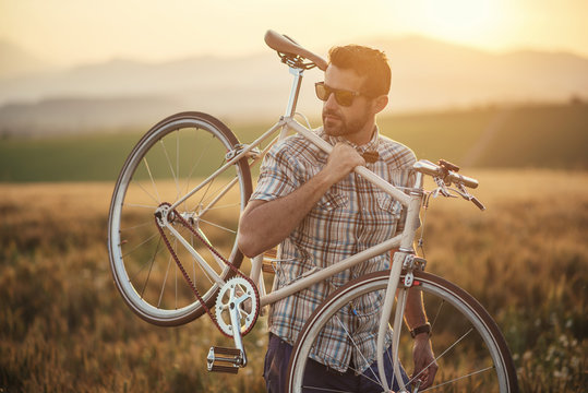 young man with retro bicycle in sunset on the road, fashion photography on retro style with bike