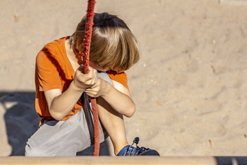 Young boy hanging on a swing at outdoor playground