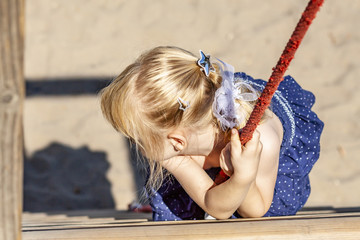 Young girl hanging on a swing at outdoor playground