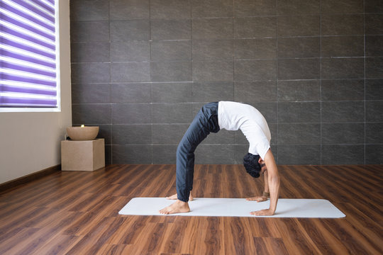 Experienced yogi doing wheel yoga pose in gym. Man practicing yoga. Yogi concept. Side view.