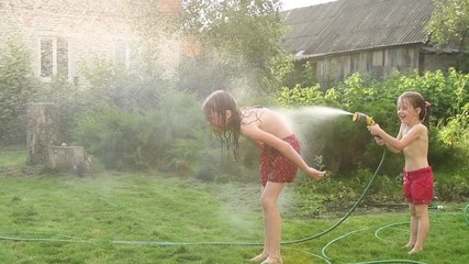 fun water game of two girls at garden in summer