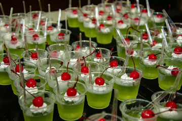 green jelly dessert with whipped cream and cherry