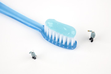 two miniature dentists inspecting toothbrush