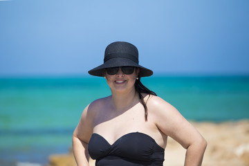 Portuguese woman with hat and black glasses with blue sea truquesa background.