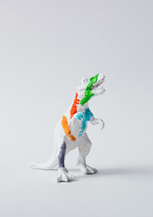 White dinosaur painted with vivid colors. Minimal surreal fun school concept.