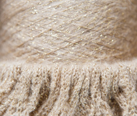 Nude and gold colour spool of thread on the knitted textile background