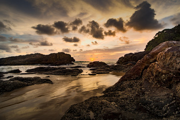 HDR processed dramatic sunset over sea beach on south islands in Thailand with a natural rock in the foreground.