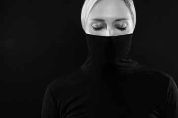 Fototapeta na wymiar Black and white portrait of woman hiding face in black turtleneck