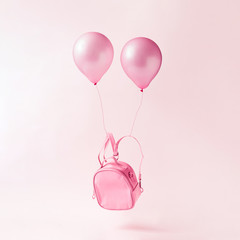 Pastel pink school bag with balloons floating. Surreal modern still life. Back to school minimal concept.