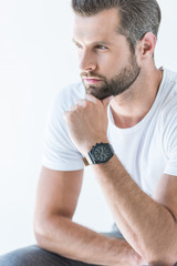 bearded pensive man in white t-shirt with wristwatch, isolated on white
