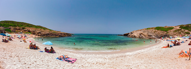 Panoramic view of the beach of "Porto Palmas" in Sardinia, Italy, with some sunbathers lying in the sun