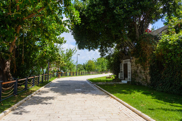 alley promenade along the promenade and the walls of the ancient city. tall green trees. Side, Turkey