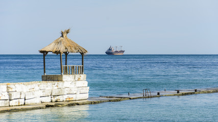 Hut in a pier with a tanker in the horizon.