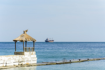 Hut in a pier with a tanker in the horizon.