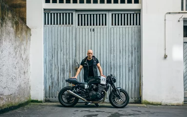 Acrylic prints Motorcycle Builder posing with a custom motorcycle in front of the garage door