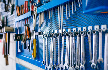 Detail of motorcycle workshop tools board with wrenches in the foreground - obrazy, fototapety, plakaty