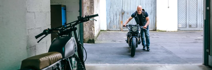 Acrylic prints Motorcycle Front view of biker taking custom motorbike to the garage
